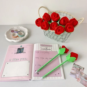 Detail of creative rose-shaped ballpoint pens with green ribbon wrap and red velvet petals