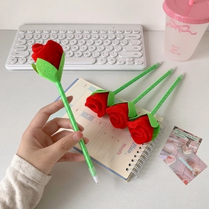 Detail of red rose ballpoint pens with velvet petals on a desk with stationery