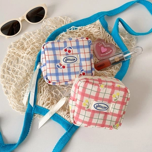 Detail of square checkered pouches with cherry and floral prints next to cosmetics