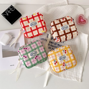 Plaid fabric organizer bags with cherry patterns and ribbon zippers on gauze background