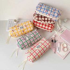 Detail view of colorful checkered cherry pencil cases with elegant white ribbon zippers