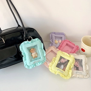 Close-up of pastel ruffle photocard holder hanging on a black leather handbag handle