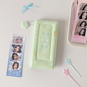 Close-up of green K-pop photocard album with ribbon design and clover charm