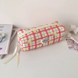 Close-up of red checkered pencil case with cherry patterns and decorative cream ribbons