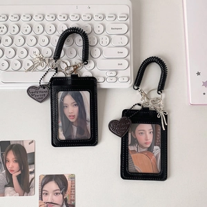 Black faux leather card holder set with heart charms and spring lanyard on desk