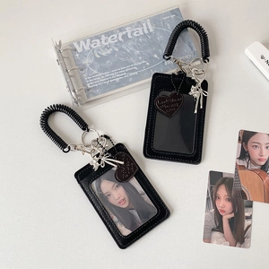 Close-up of black leather card holder with spring lanyard, cat charm and heart pendant