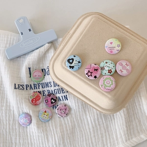 Close-up of mini 25mm clover tinplate badges with cute peach and heart patterns