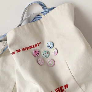 Set of six clover themed macaron colored mini badges pinned on a canvas tote bag