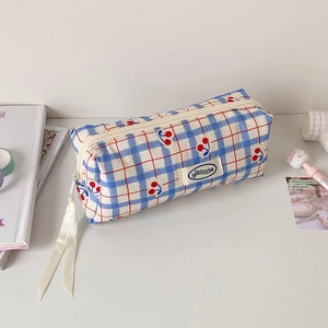 Close-up of blue plaid pencil case with cherry print, Hisocute label and ribbon zipper
