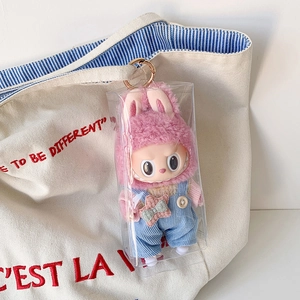 Transparente PVC-Tasche mit süßer Plüschpuppe an einer Canvas-Tasche für unterwegs