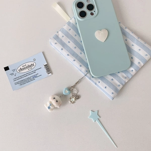 Détail d'un mignon pendentif chien en peluche blanc avec cœur bleu et étoile pour portable