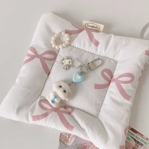 Porte-clés chien en peluche blanche avec cœur bleu et perles sur tapis rose matelassé