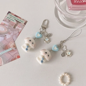 Détail de porte-clés chien en peluche avec breloques cœur et étoile bleues