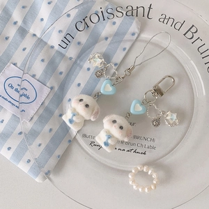 Détail de porte-clés chien en peluche avec accents de cœur bleu sur plateau en verre