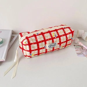Detail of red checkered pencil case with yellow cherries and white ribbon zipper pull