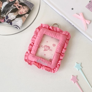 Detailed view of pink fabric card holder with ruffled edges and metallic hanging ring