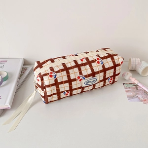 Close-up of checkered pencil case with cherry print and white ribbon zippers