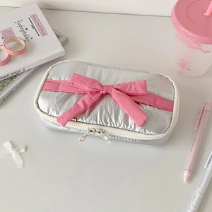 Detailed view of silver metallic pencil case with pink bow and white zipper closure