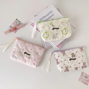 Detailed flat lay of three quilted mini bear pouches with colorful zippers and ribbons
