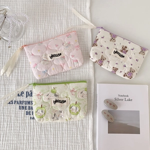 Detailed view of quilted cotton pouches in pink, beige, and green with cute cartoon prints