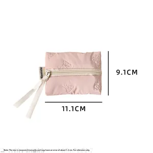 Detail of pink quilted mini coin pouch with 3D butterfly pattern and white zipper pull