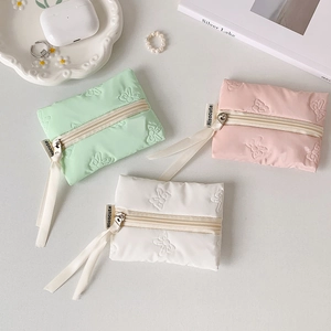 Detail of quilted bow texture and ribbon zipper on pastel mini storage pouches