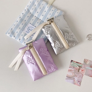 Detailed view of silver and purple bow-embroidered mini pouches for makeup and cables
