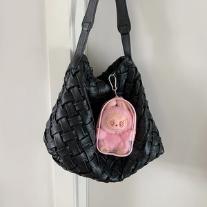 Detail of black woven shoulder bag featuring a pink transparent doll display charm