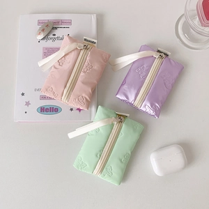 Detailed view of mini bow-embossed pouch in pink, purple and mint green with ribbon zip