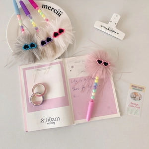 Close-up of fluffy plush pompom ball pens with heart-shaped sunglasses and colorful beads