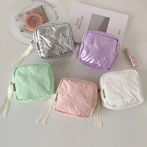 Flat lay of small bow-embossed cosmetic bags in five colors with ribbon zipper pulls