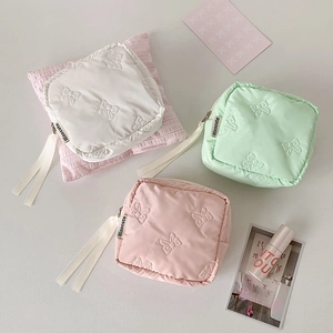 Detailed view of square makeup bags with bow textures and ribbon zipper pulls