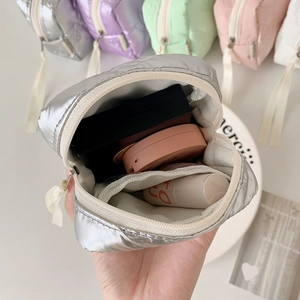 Quilted bow makeup bag with ribbon zipper, shown open with cosmetics inside