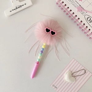 Détail d'un stylo à pompon rose avec lunettes coeur et perles colorées dans le corps