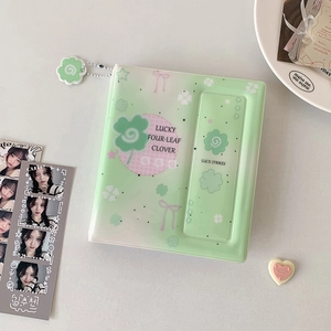 Close-up of mint green clover photocard binder with lucky four-leaf clover pendant