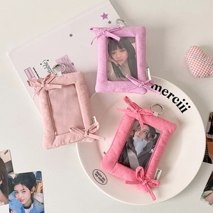 Close-up of plush bow photocard holders with metal keychains in pink and purple colors