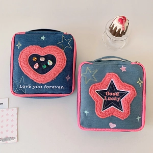 Detail of denim cosmetic bags with plush heart and star embroidery and pink zip handles