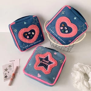 Detailed embroidery and heart sequin accents on a denim makeup bag with pink faux fur trim