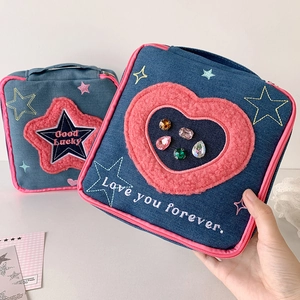 Detail of blue denim cosmetic bag with star embroidery, pink plush heart and crystals