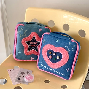 Close-up of denim cosmetic bags with pink star patches and heart rhinestone details
