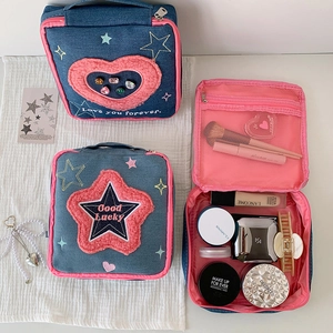 Detail of denim cosmetic bags with embroidered stars, plush hearts and pink zippers