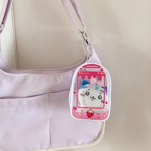 Clear strawberry bag with plush cat charm hanging on a light purple shoulder strap