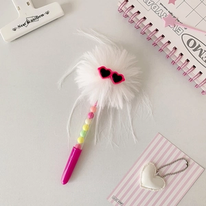 Détail d'un stylo bille créatif avec pompon blanc et lunettes de soleil coeur roses