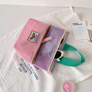 Nahaufnahme der bonbonfarbenen Netztasche mit Bärenaufnäher und grünem Griff
