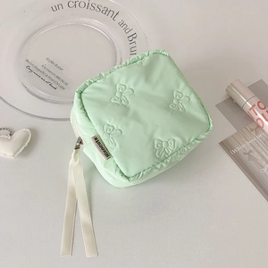 Detailed view of mint green quilted bow pattern cosmetic bag with ribbon zipper pulls
