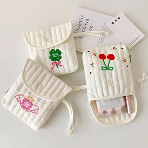Flat lay of three quilted fabric pouches featuring clover and cherry embroidery details