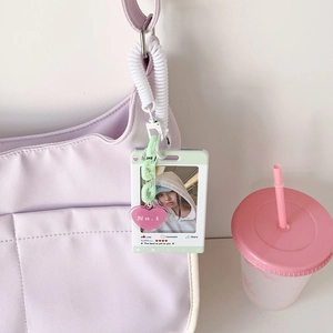 Grüner Fotokartenhalter mit pinkem Herzanhänger an einer lila Segeltuchtasche