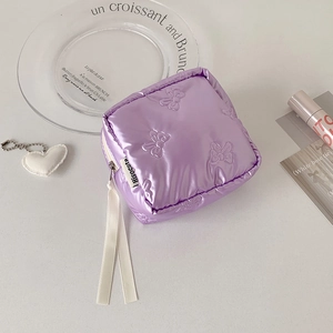 Detail of quilted purple pouch featuring embossed bow patterns and soft silk ribbon zipper