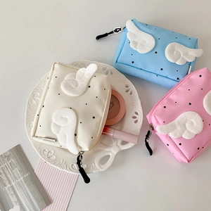 Detail of mini canvas pouches with plush angel wings and star prints in macaron colors