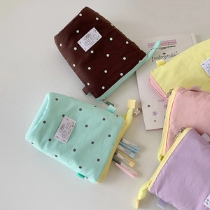 Detailed close-up of macaron-colored fabric pencil cases with dots and zipper straps